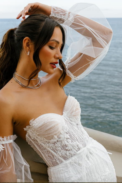 model wearing a strapless white wedding gown with detachable sleeves and pearl beaded bodice
